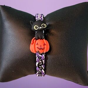 Black cat on a pumpkin Halloween adjustable bracelet; purple black & white cord